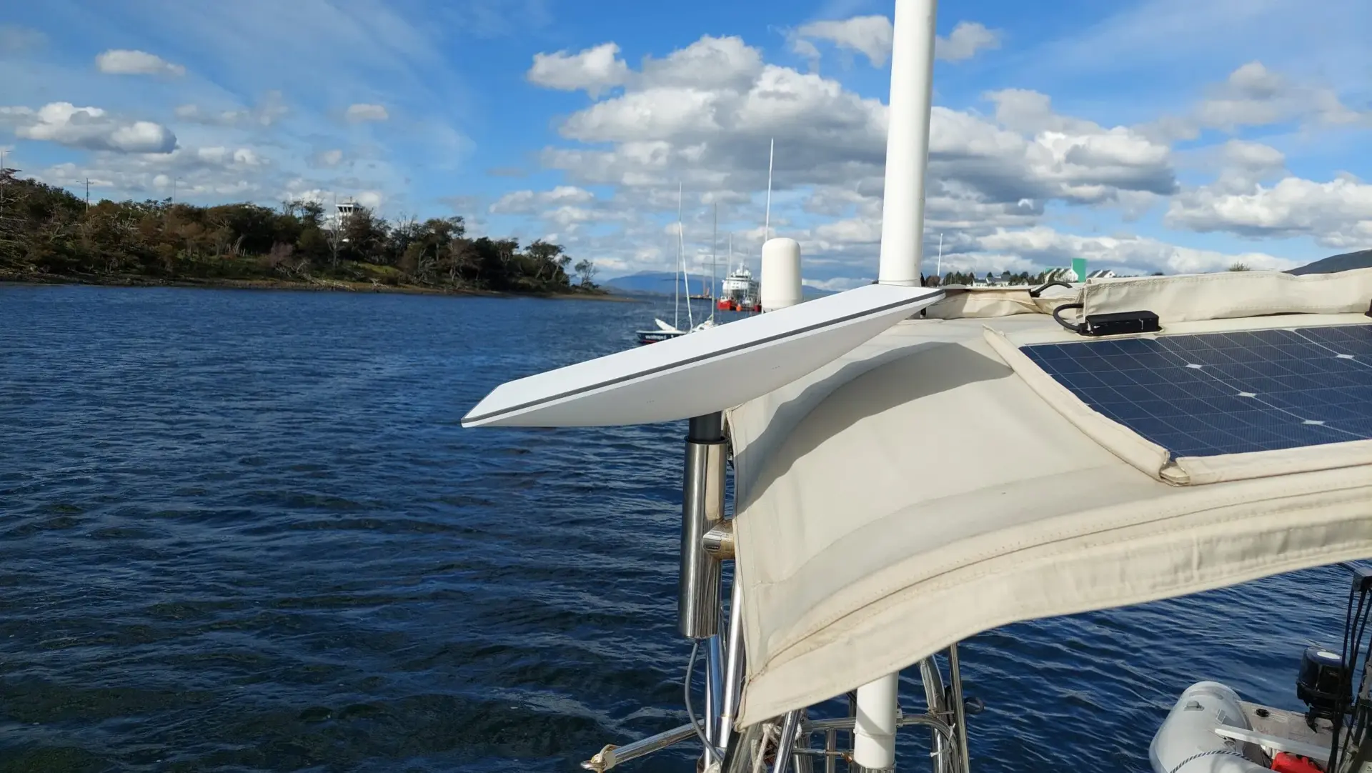 Starlink Mini mounted on a sailboat rail next to a solar panel on the water