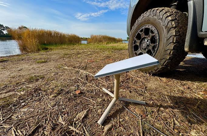 Starlink Mini on a portable tripod stand beside a truck at a rural riverside site